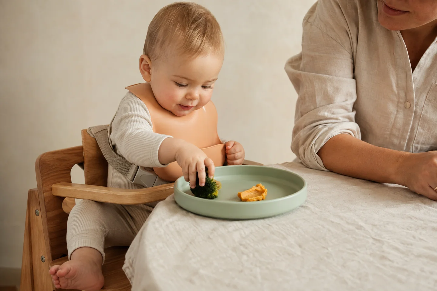 Un bebé explora la comida junto a una persona adulta. Escena ilustrativa.
